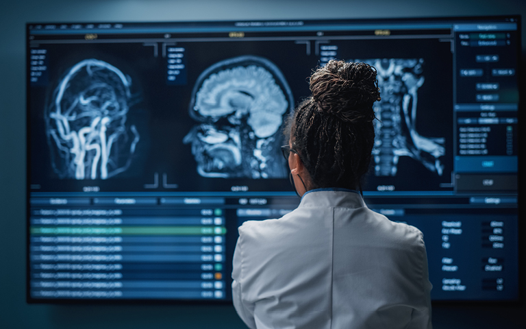 Photo: Black Female Doctor Looking at TV Screen, Analyzing MRI Images