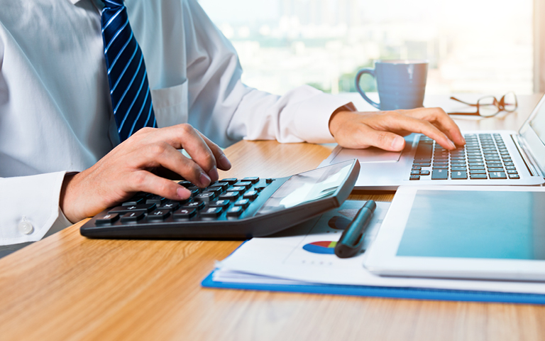 photo: man at computer using calculator