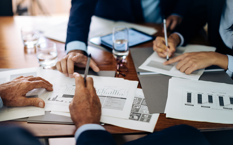 Boardroom table close up of paperwork, charts and graphs
