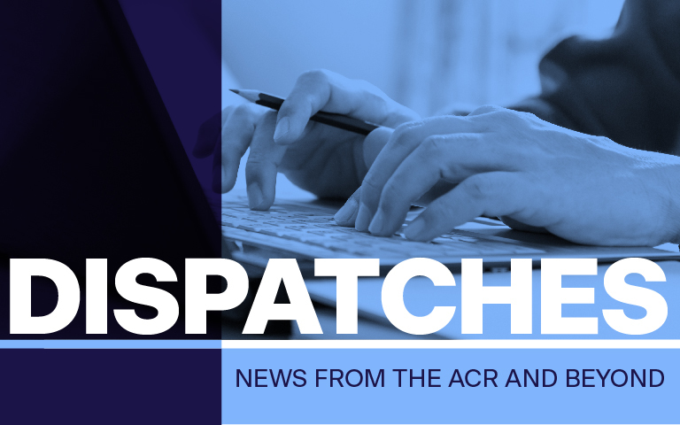 Blue tinted photo of journalist's hands at a computer