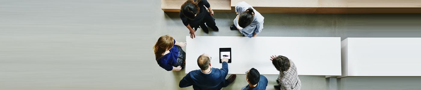 group of six men and women gathered around a tablet