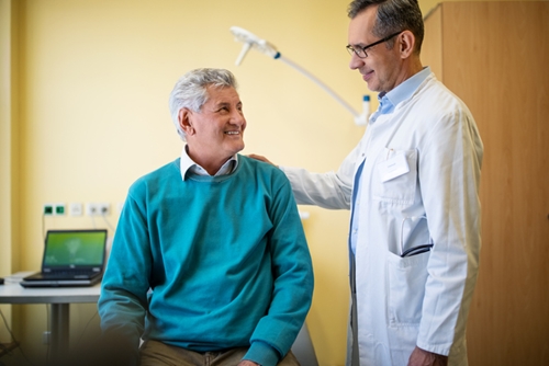 Doctor patting older man that is sitting on the back 