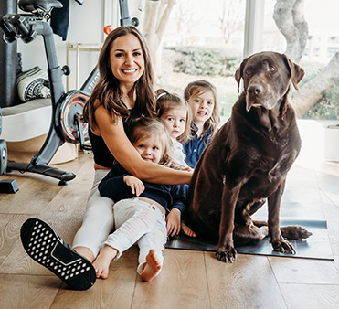 Nilda Maria Williams, MD, MS sitting the floor with her 3 daughters and dog